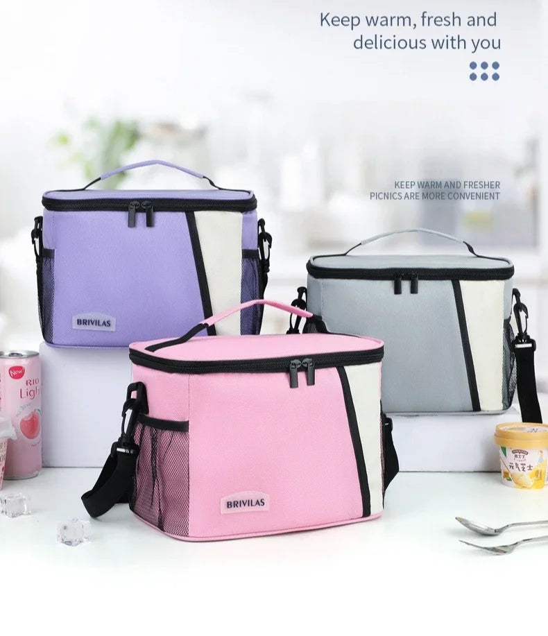 Three insulated reusable lunch bags in purple, pink, and gray are displayed on a white surface.