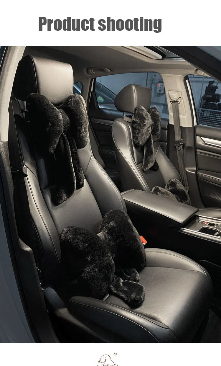 Interior view of a car seat showing a black leather seat with fuzzy bowknot headrest pillows and lumbar support.
