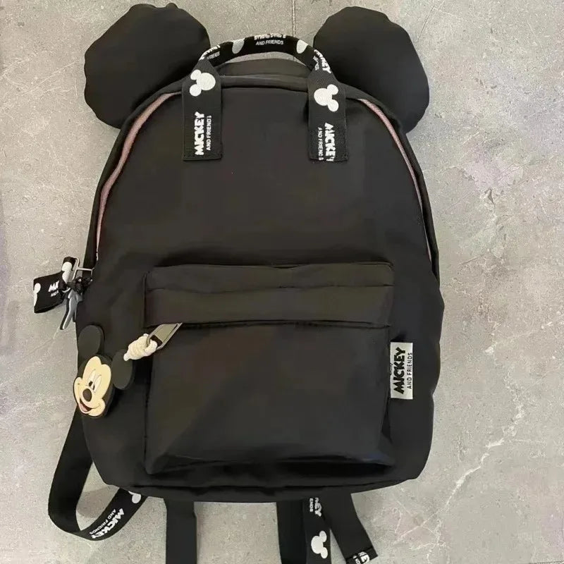 A black Mickey Mouse-themed fashion backpack with a large front pocket and shoulder straps.