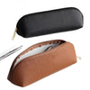 A brown leather makeup pouch with a zipper and a black leather pencil case shown next to each other.