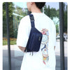 Une personne portant un petit sac imperméable bleu marine sur un t-shirt blanc, en extérieur.