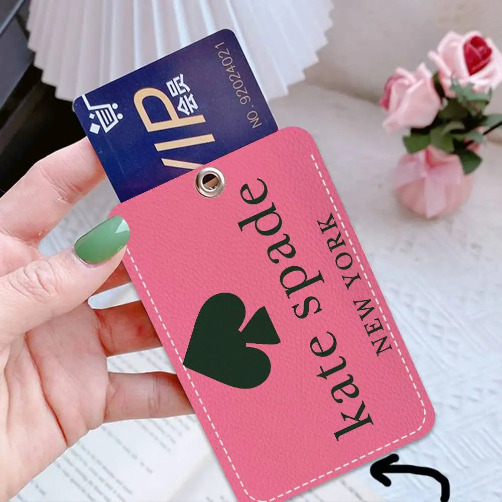 A pink card holder with a green heart design and gold lettering is held by a hand, next to a blue VIP card.