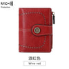 A red leather multi-fold wallet with stitching and a decorative metal emblem.