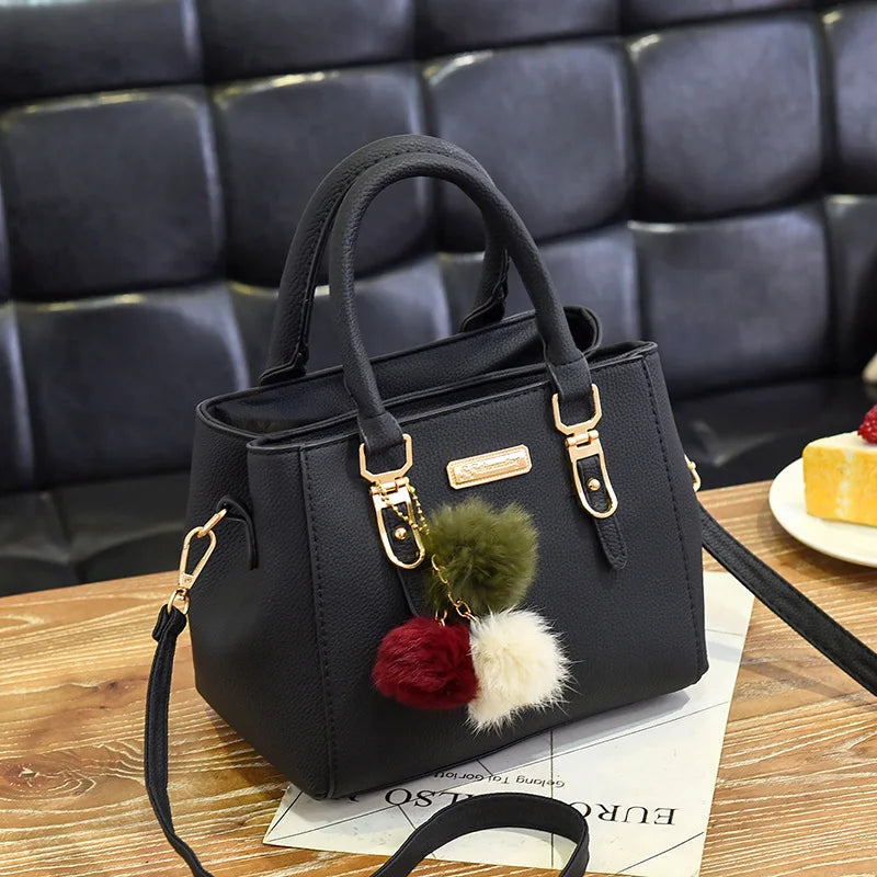 Black vintage PU leather tassel handbag with gold hardware resting on a wooden surface.