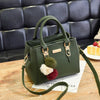 A dark olive green vintage PU leather tassel handbag resting on a wooden surface.