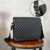A black patterned flap crossbody bag is displayed on a wooden stool with a close-up of the strap detail.