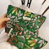 A green fabric pouch with a botanical print featuring leaves and small flowers is held by a hand.