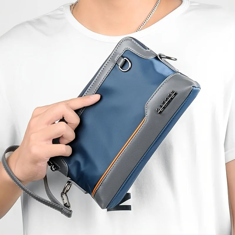 A hand holds a blue and gray everyday crossbody bag against a white t-shirt.