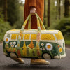 A person holds a quilted travel duffle bag with yellow and green floral patterns in an outdoor setting.