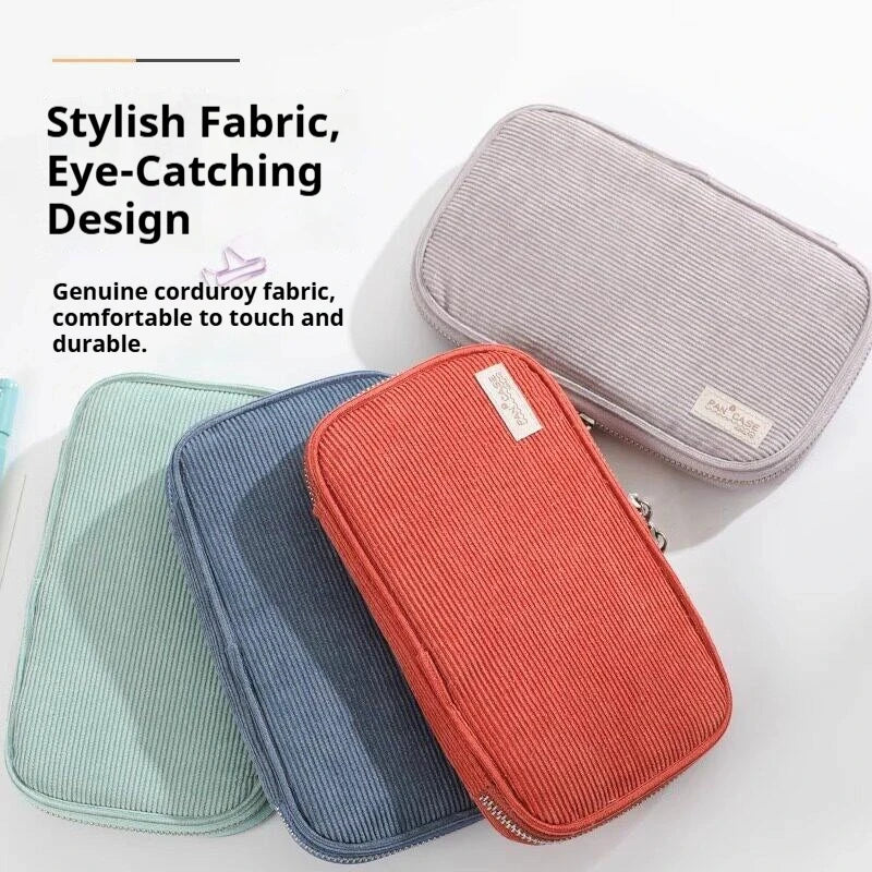 Three colored corduroy pencil cases, including pink, blue, and green, displayed on a white surface.