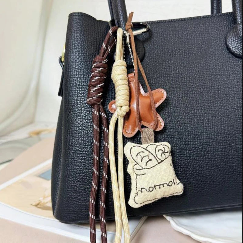 Bolso negro con corazón de bordado de cuero marrón y lino beige sujeto al asa.