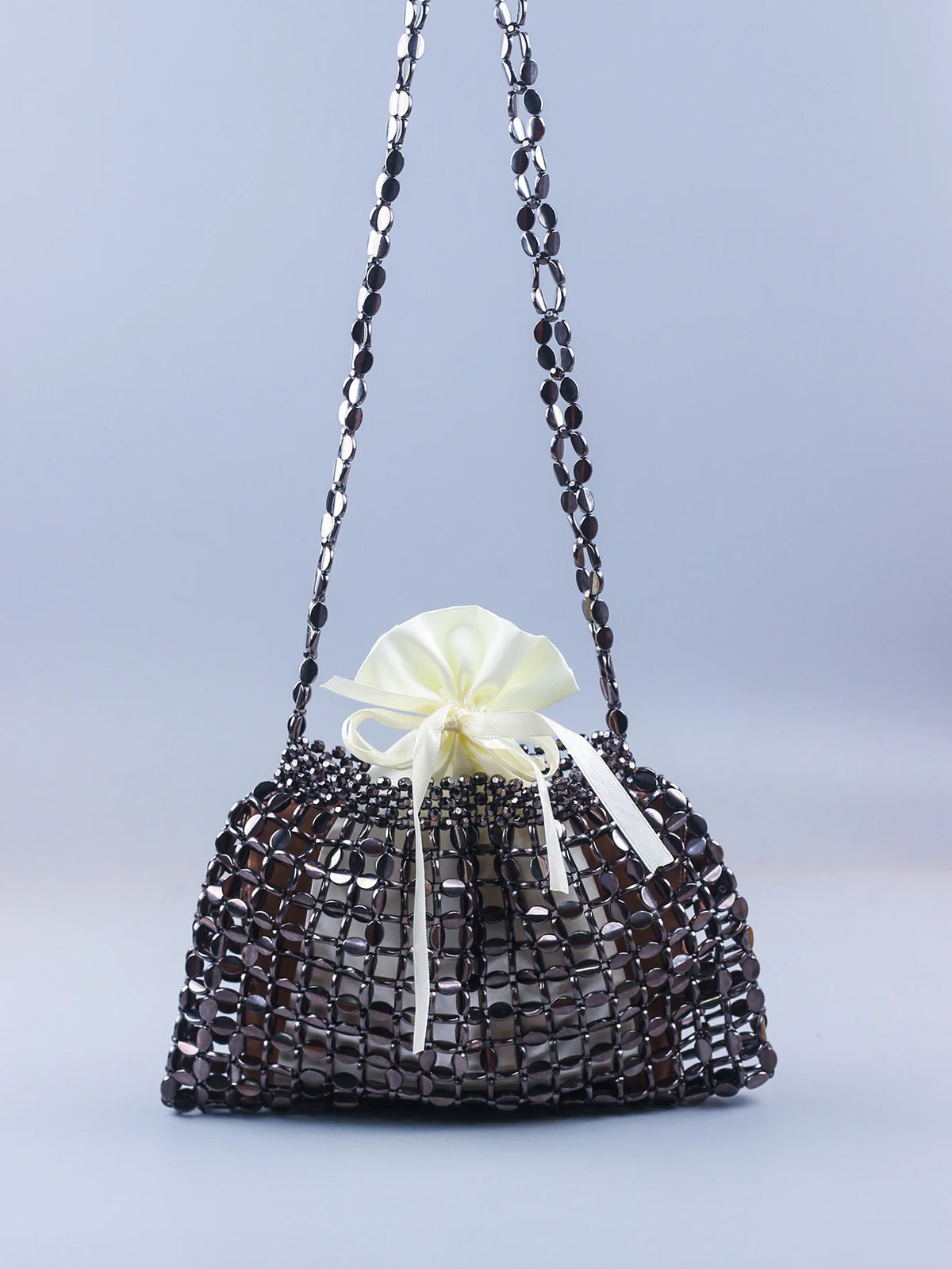 A handmade dumpling bag made of silver and gold beads with a white ribbon drawstring.