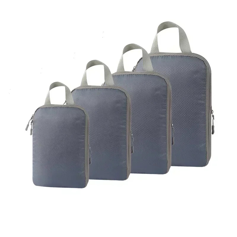 A set of four gray travel compression packing cubes with fabric handles.