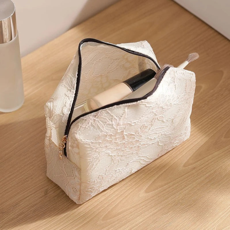 A white lace mesh cosmetic and jewelry organizer bag is shown open, holding a cosmetic bottle and a brush on a wooden surface