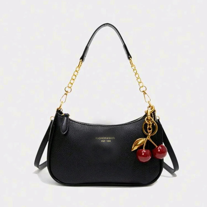 Black leather crescent crossbody bag with gold chain strap and red cherries embellishments