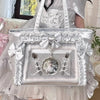 A silver and white transparent shoulder tote bag with a bow detail carried by a person wearing a light pink dress.