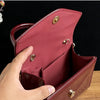 A hand opens a maroon glossy texture evening handbag, showing the interior lining and hardware.