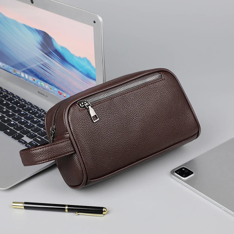Pochette de soirée en cuir PU marron foncé avec fermeture éclair et sangle, posée à côté d'un ordinateur portable.
