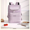 A light purple insulated travel backpack with black straps and a quilted pattern sitting on a white table.