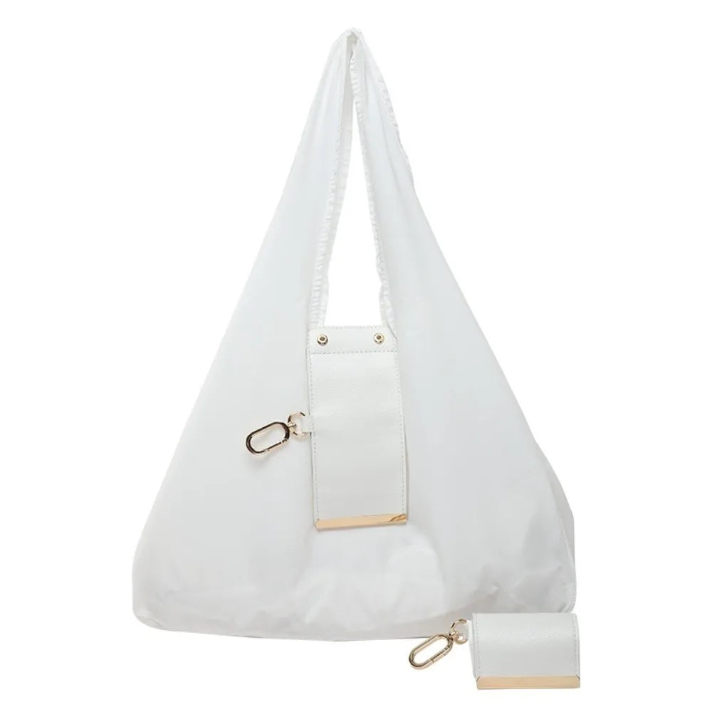 A white reusable nylon mini keychain tote bag with a padded shoulder strap and gold hardware.