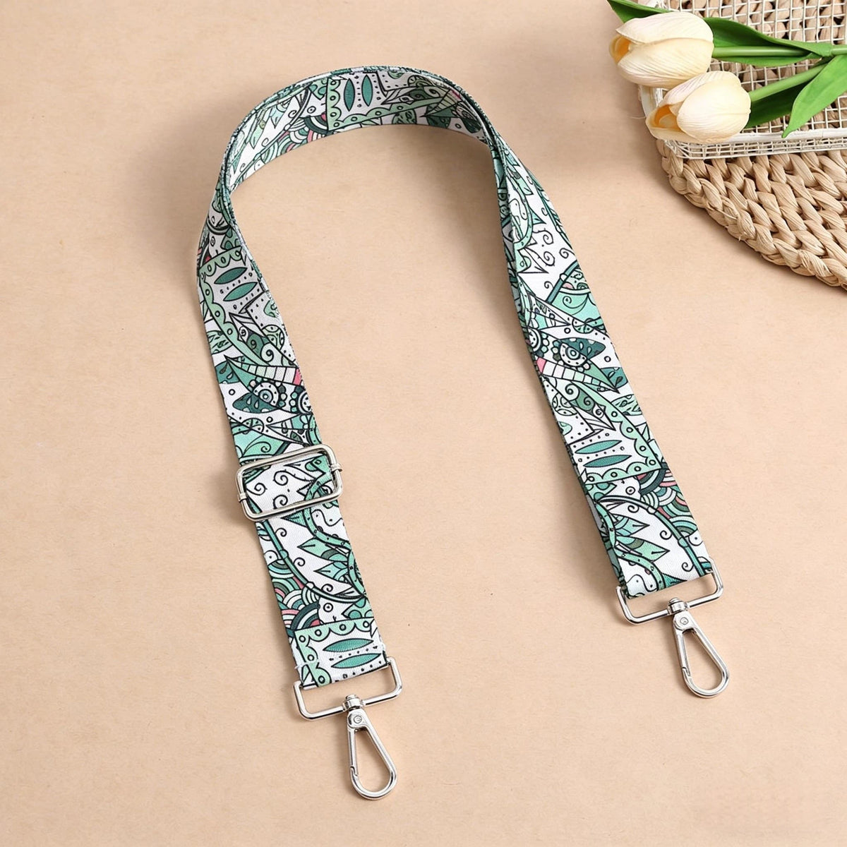 A beige crossbody strap with a bohemian patterned fabric featuring green and white designs.