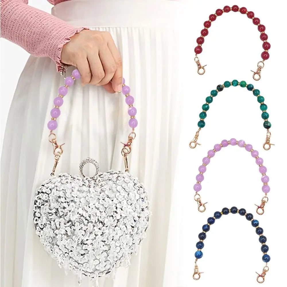 A silver heart-shaped bag chain made of sparkling stones is displayed against a white skirt.