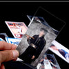 A hand holds a transparent card sleeve protector featuring a portrait of a person in a dark outfit.