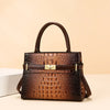 A brown crocodile embossed leather shoulder handbag with a dark brown strap and gold hardware.