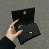 A hand holds an open black card holder wallet with gold accents against a gray background.