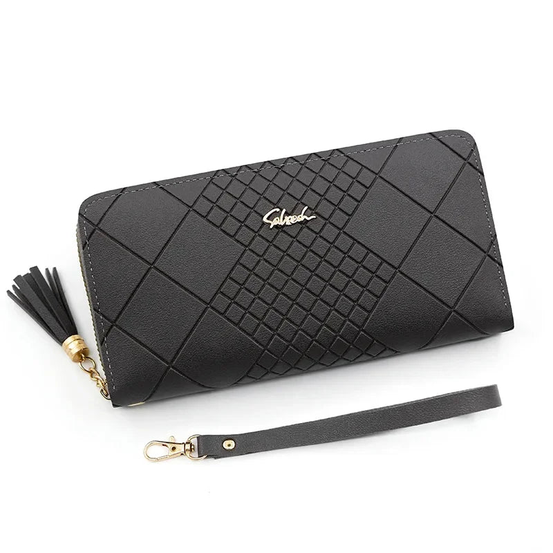 A black quilted clutch wallet with gold hardware and a leather strap is shown on a white background.