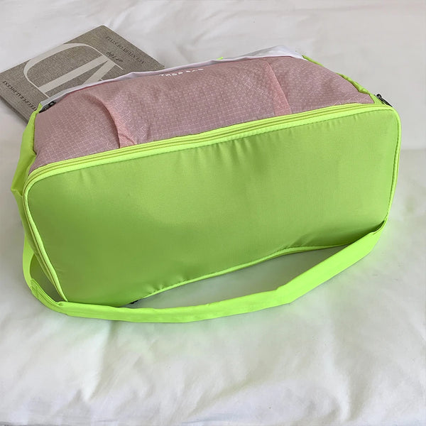 Limettengrüne ausklappbare Reise-Tasche mit rosa Innenfutter und dünnem Riemen auf weißem Untergrund
