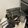 A black patterned women's rivet waist bag is displayed next to a black book on a white surface.
