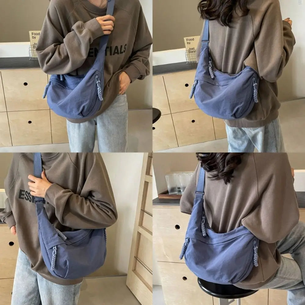 A person wearing a brown sweatshirt is holding a blue canvas crossbody shoulder bag.