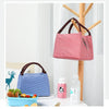 A red and white striped oxford cloth thermal lunch bag hanging on a wooden rack with various food items nearby.