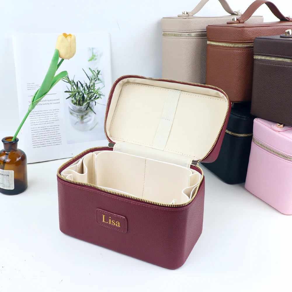 A maroon makeup bag with a gold zipper and a beige interior is shown next to other leather accessories.