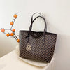 A dark brown faux leather tote bag with a monogram print is displayed against a white wall.