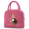A pink insulated canvas lunch bag featuring a gold letter A design with a small floral arrangement.