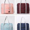 Trois versions d'un sac de voyage pliable en rose, marron et bleu marine.