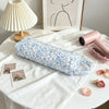 A light blue floral quilting storage bag lying on a white cloth next to a pink hair dryer and framed artwork.