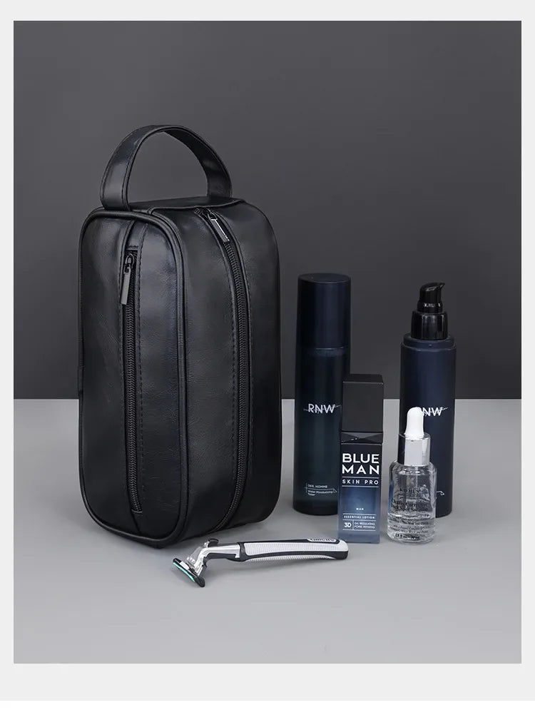 A black leather travel cosmetic bag is shown with a bottle of Blue Man skin product and a silver grooming tool.