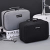 A black portable waterproof travel toiletry bag next to a grey one and a sink.