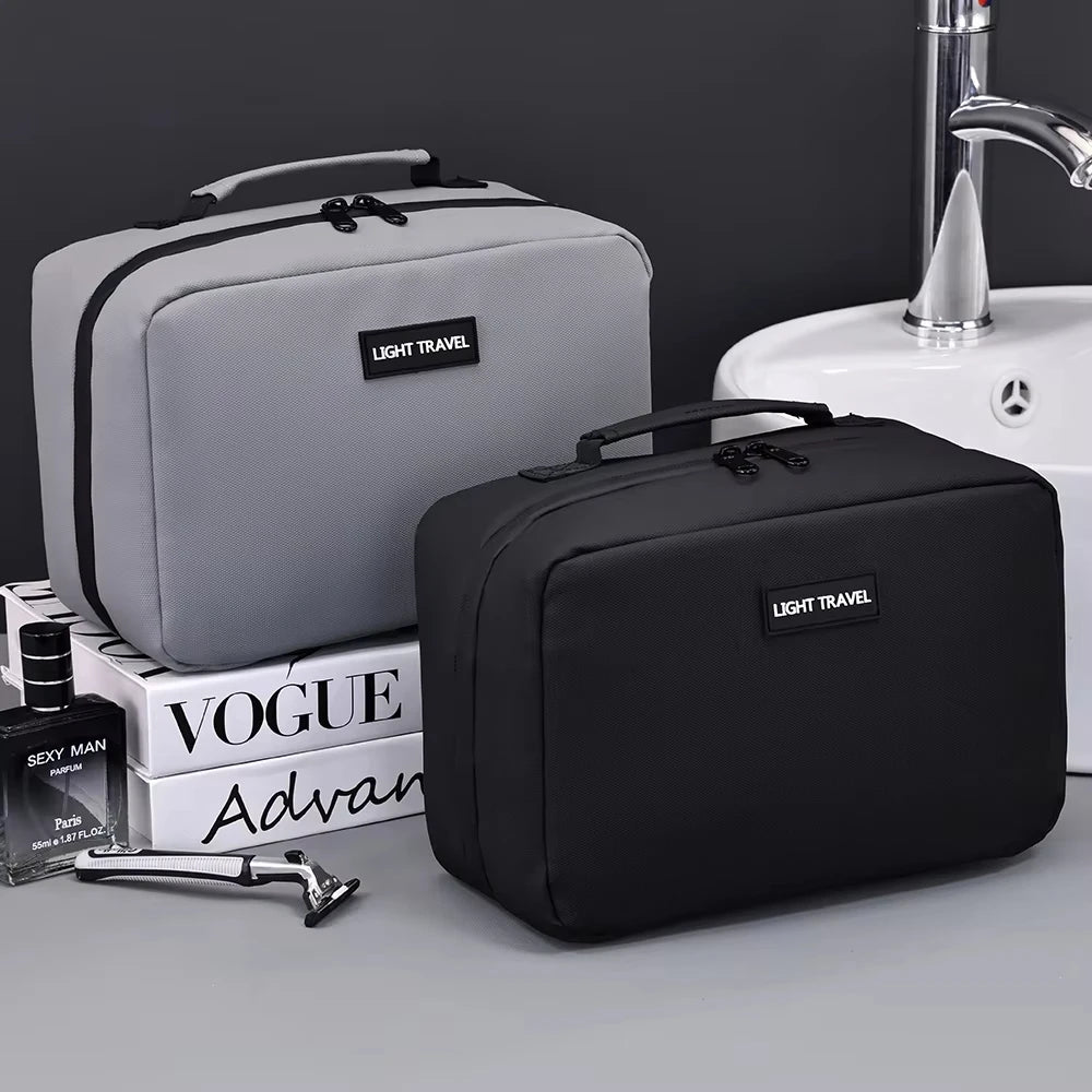A black portable waterproof travel toiletry bag next to a grey one and a sink.