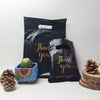 Black bulk thank you gift bags with gold lettering next to a succulent and pine cone