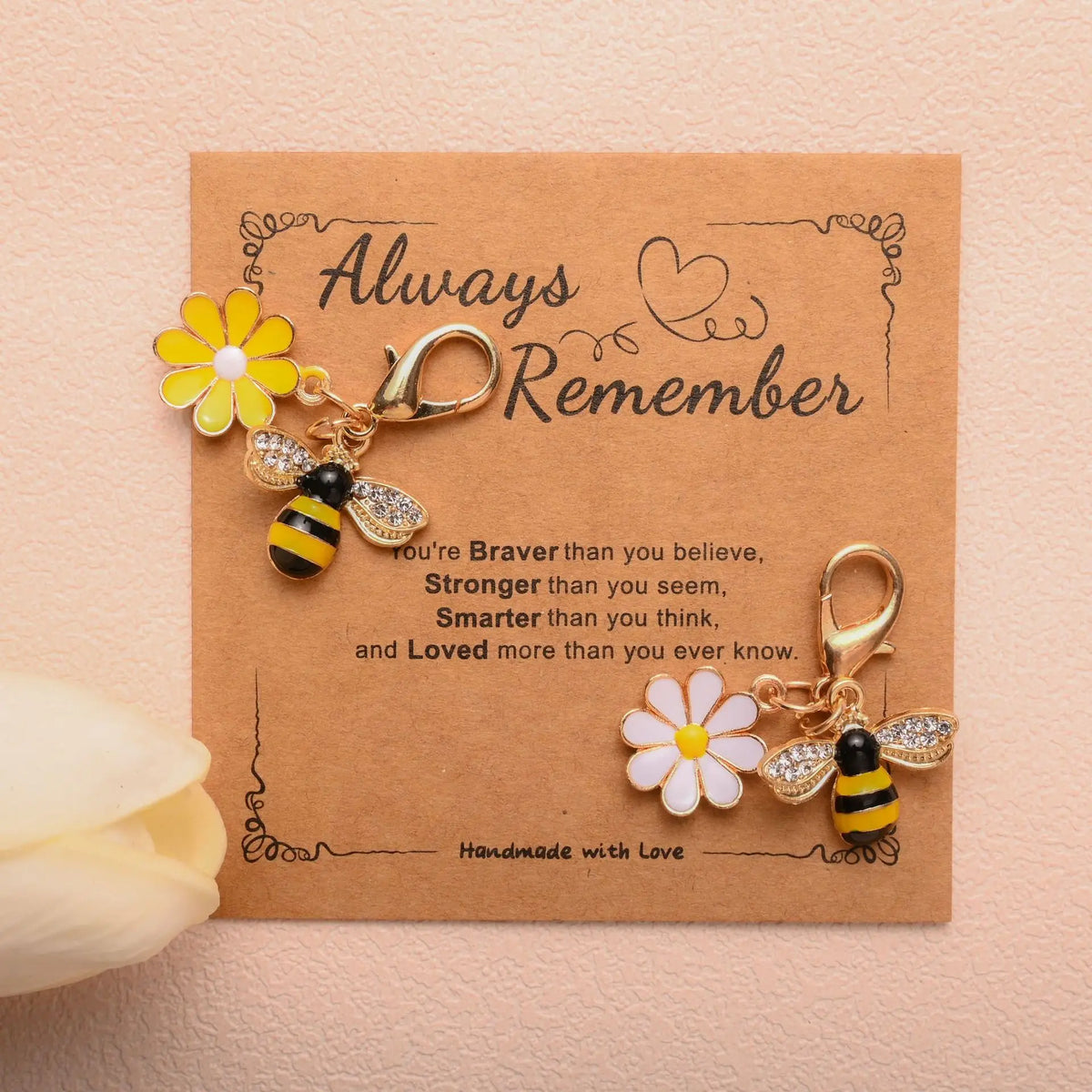 A handmade card featuring a yellow flower and bee-shaped keychains with the text Always Remember