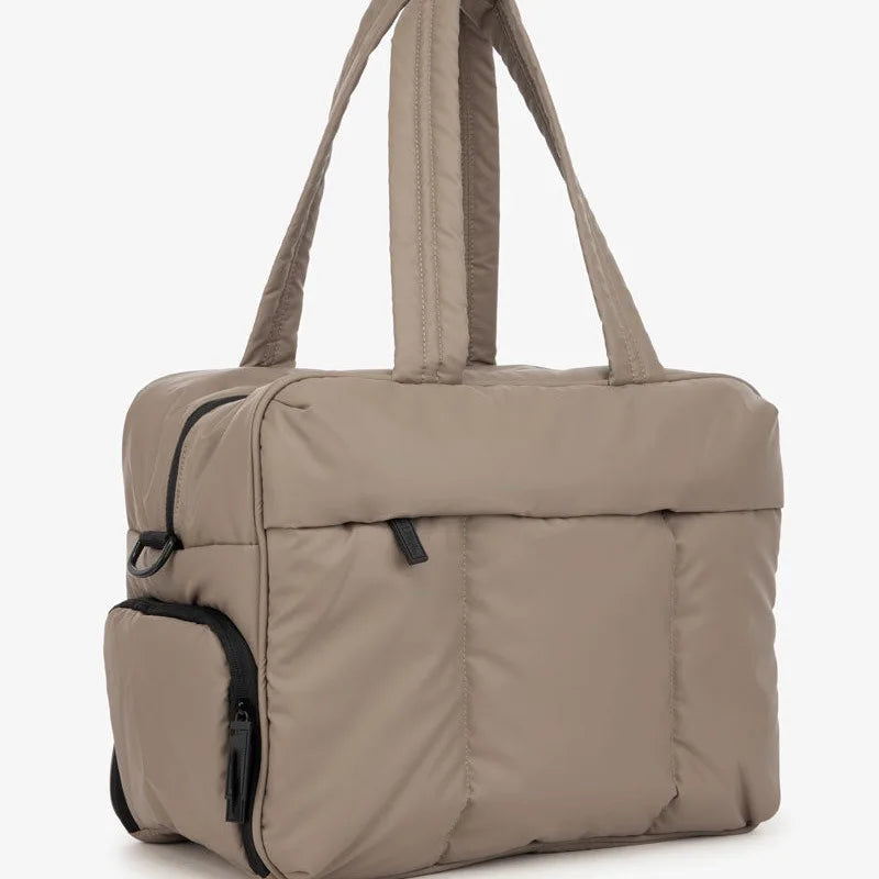 A beige large capacity women's travel duffle bag with padded compartments and carrying handles.