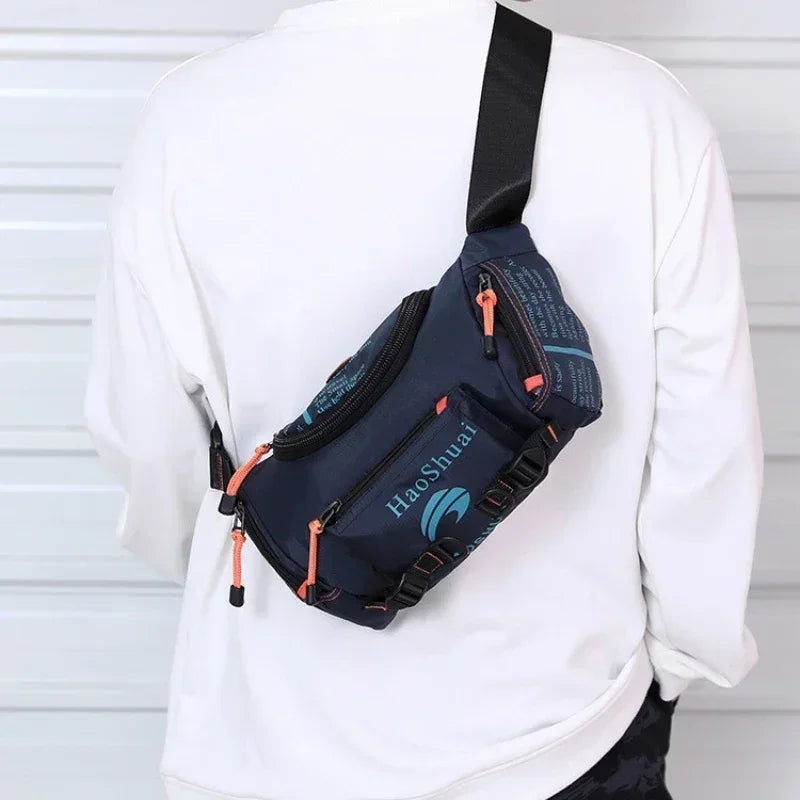 Dunkelblaue taktische Brusttasche mit orangefarbener Trageleiste, getragen über einem weißen Langarmshirt.