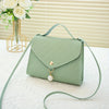 A mint green beaded square crossbody bag with a gold chain and adjustable strap resting on a white surface.