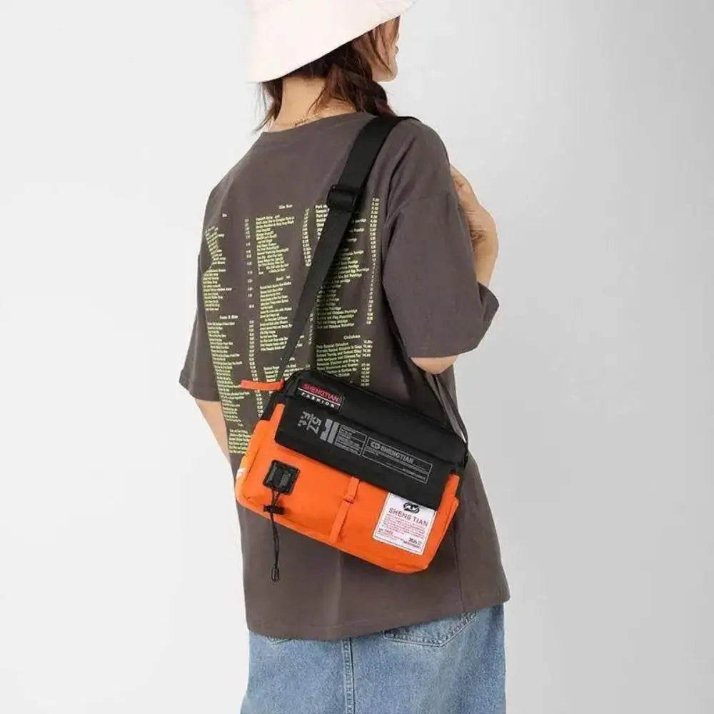 A person is wearing an orange waterproof nylon crossbody bag with a black strap and a light pink hat.