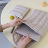 Hands are opening an embroidered cotton laptop sleeve with a soft interior on a light table.
