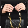 A gold chain with an alloy cherry flower bag pendant is displayed against a black quilted leather handbag.